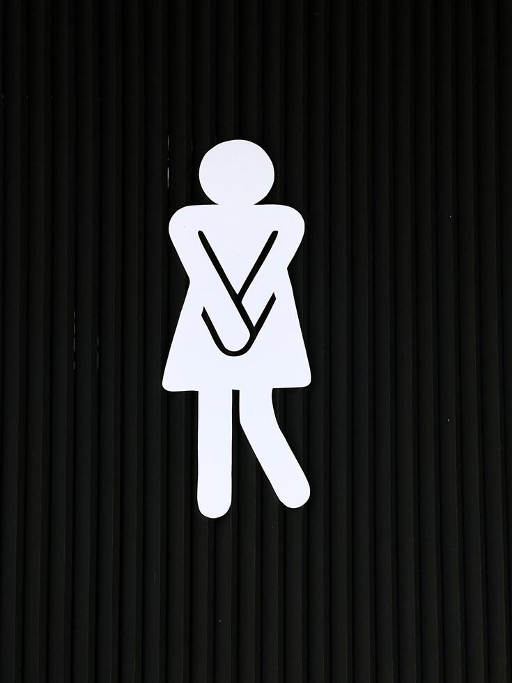 Creative Female Restroom Sign with Urgency Pose on Dark Background, Perfect for Bathroom Signage Concepts photo