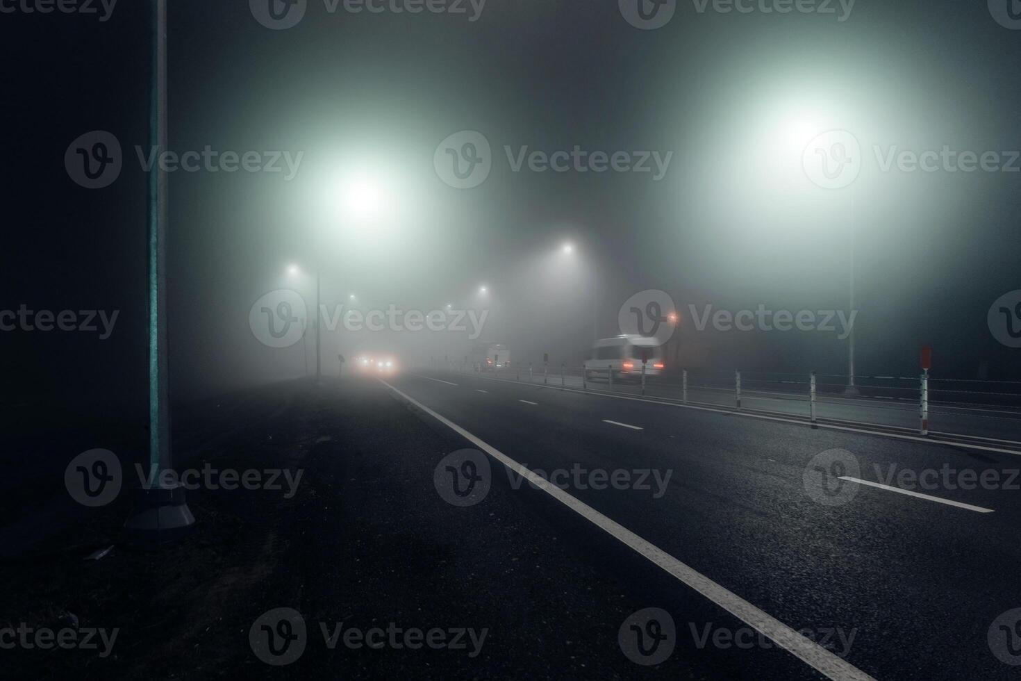 Foggy night road illuminated by street lights photo