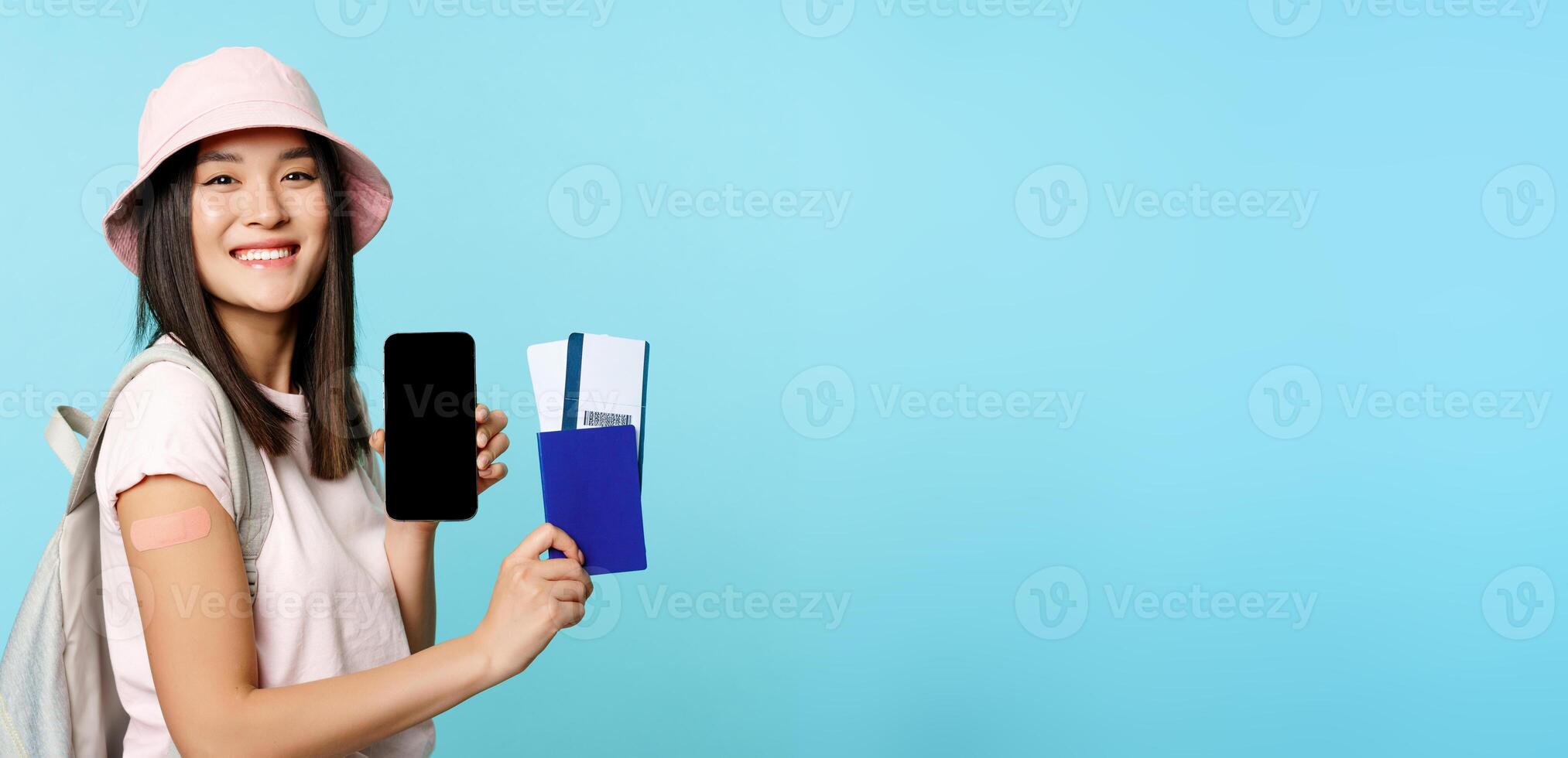 Happy smiling tourist got vaccine from covid-19, showing mobile phone screen and passport with tickets to travel abroad, vaccination certificate on smartphone app photo