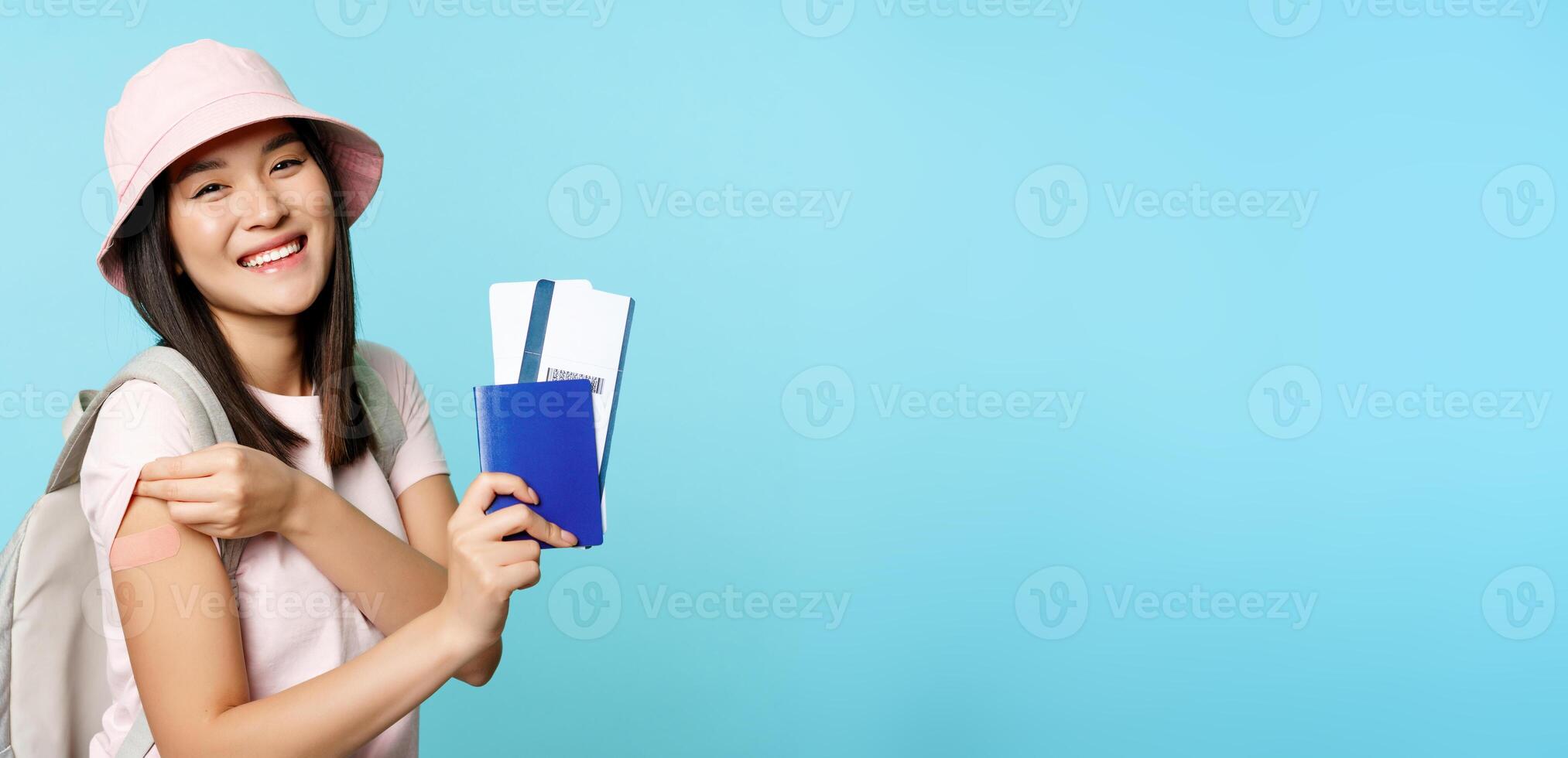 Smiling asian woman shows her passport and flight tickets, covid-19 vaccinated arm with patch, vaccinating to travel abroad, tourism and pandemic concept photo