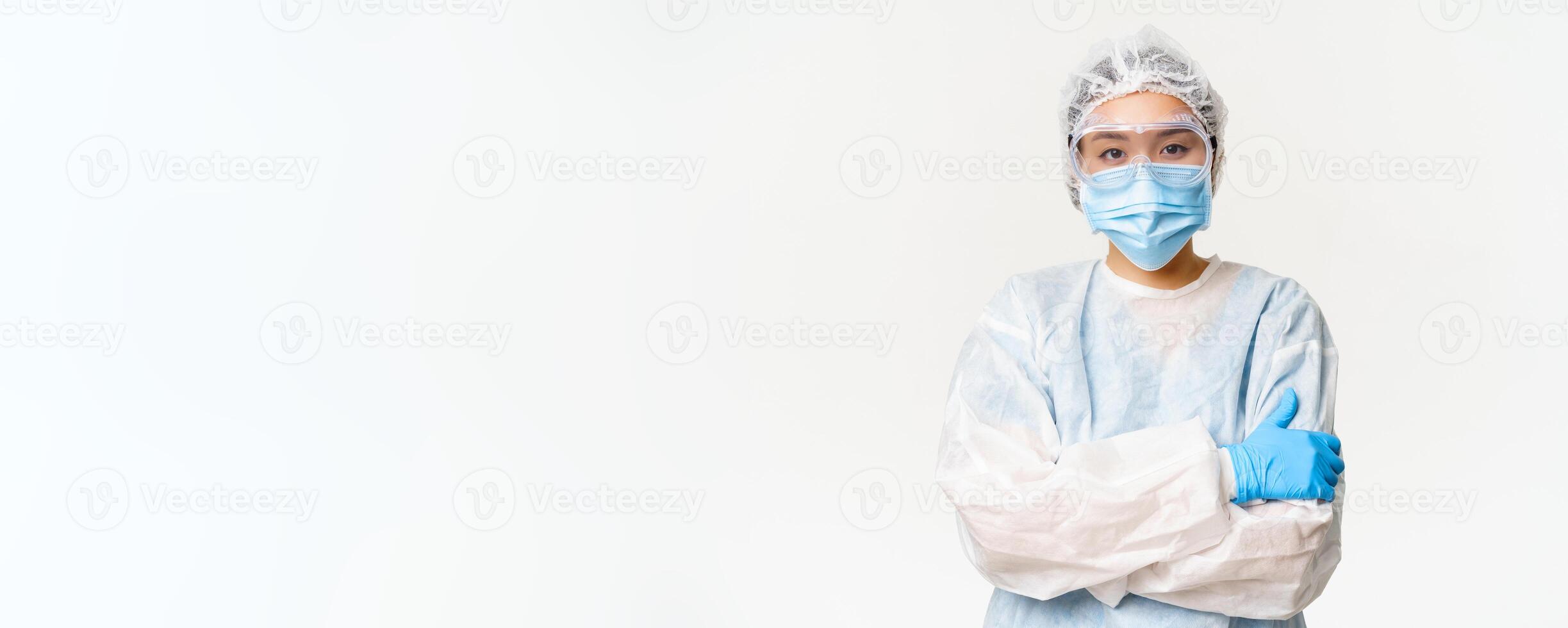 Female asian doctor or nurse in ppe, personal protective equipment from coronavirus, standing ready and confident, white background photo