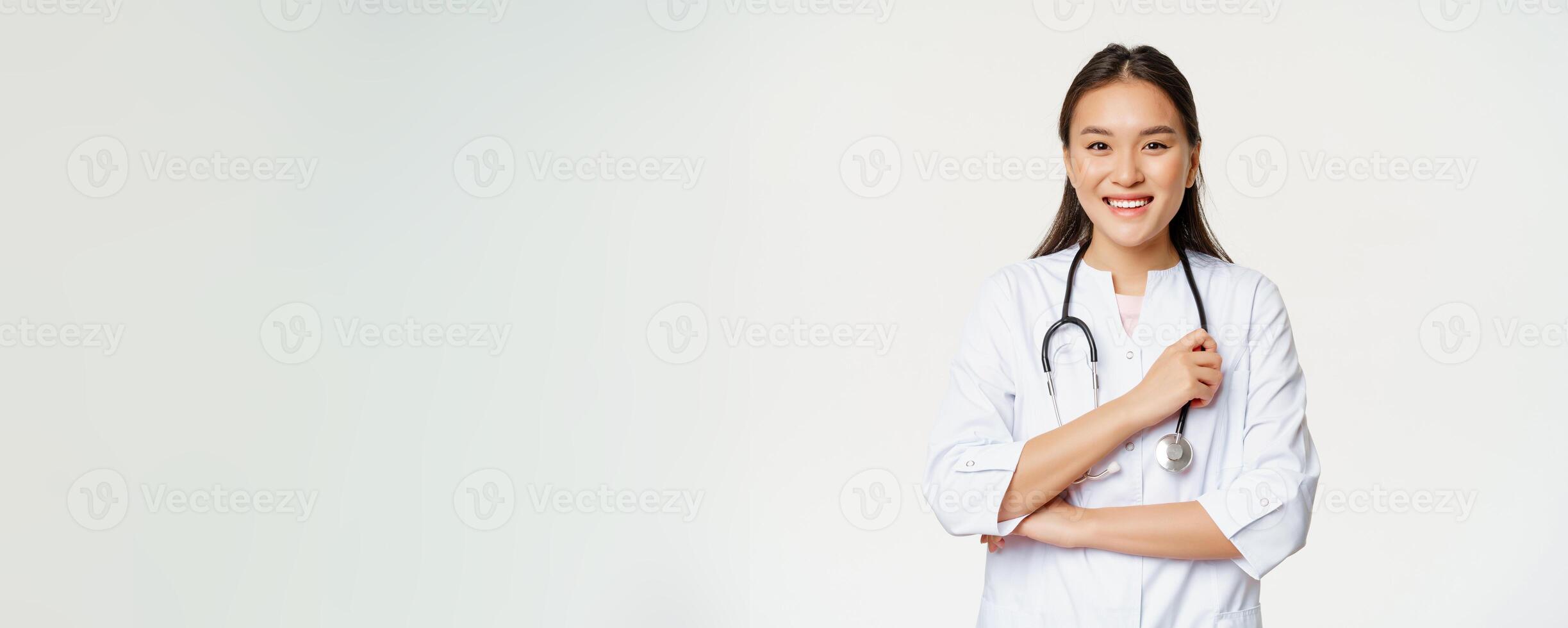 Healthcare and hospital concept. Smiling asian doctor, female nurse in uniform, looking happy at camera, standing over white background photo