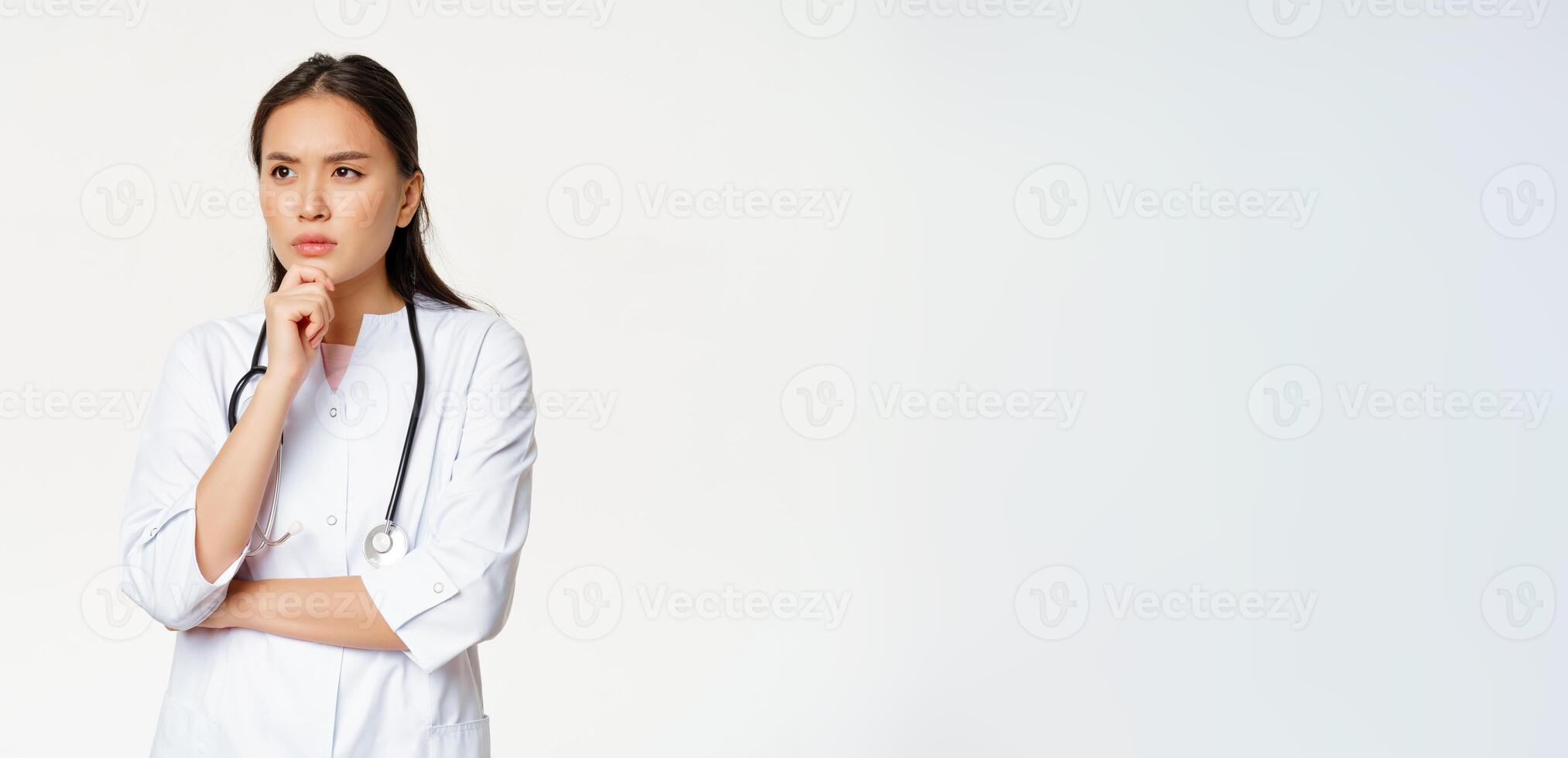 Image of serious doctor, female healthcare worker thinking, looking aside with concerned, frowning face expression, white background photo