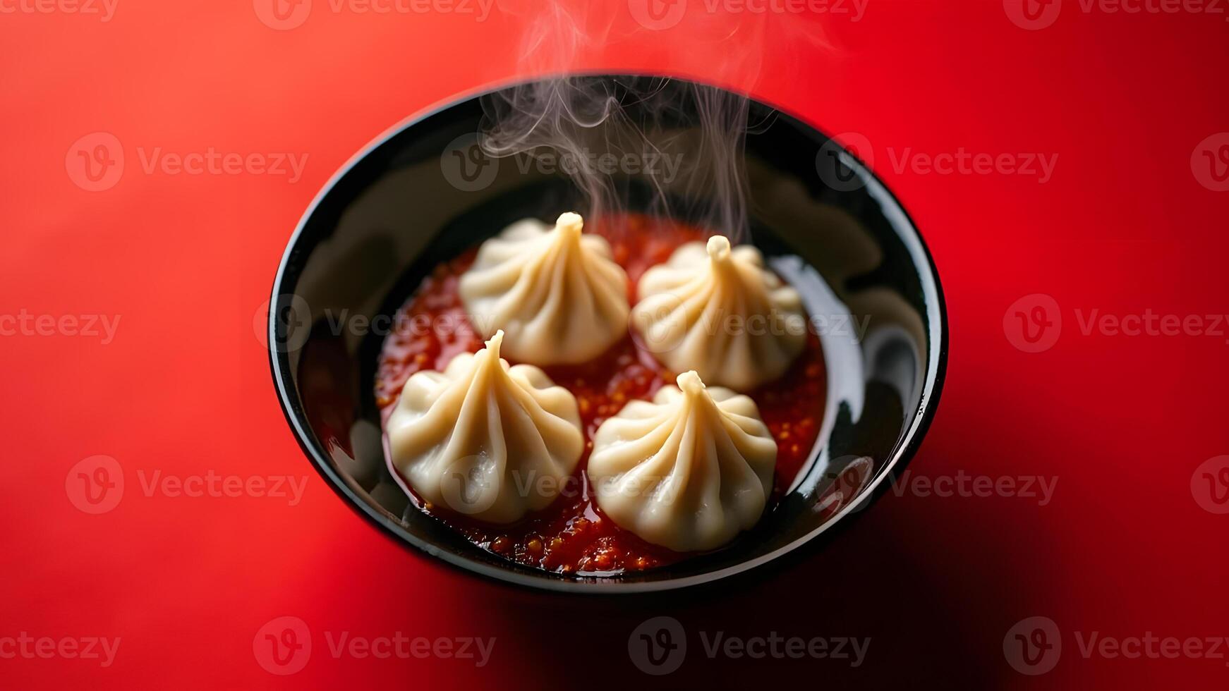 Steaming dumplings served in a black bowl, immersed in red sauce, set on a red background for a bold presentation Generated by AI photo