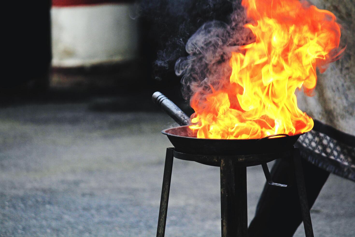 Cooking pan is blazing with a chef standing in the background with copy space. Street food on road, Burning and fire concept photo