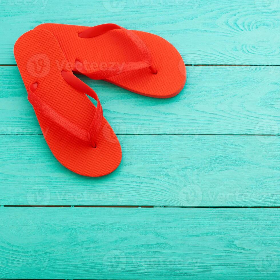 Red flip flops on turquoise wooden background photo