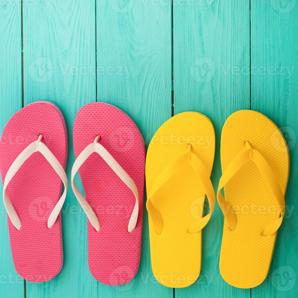 Three pairs of colorful flip flops on a wooden background photo