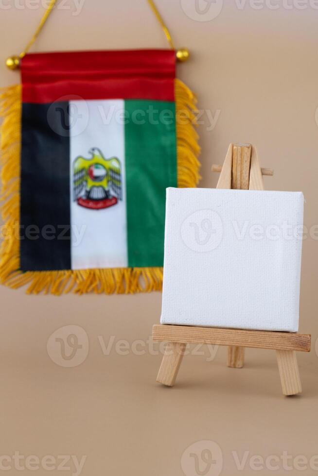 Empty white paper board Small flag of UAE on beige background with colorful envelopes. Copy space. Mock up advertisement template. Tourism travel voucher with United Arab Emirates national symbol. Visit Dubai concept photo