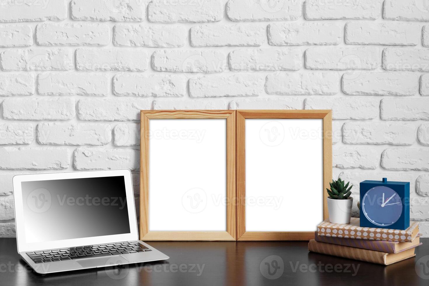 Worktable with laptop, stationery and decorations in home office with blank photo frame