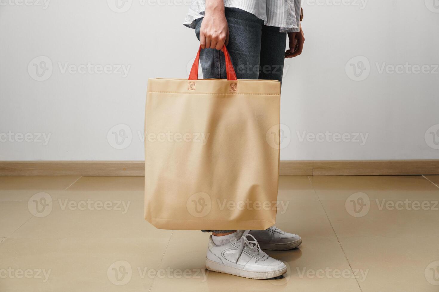 Cropped image of woman holding beige shopping bag in studio photo