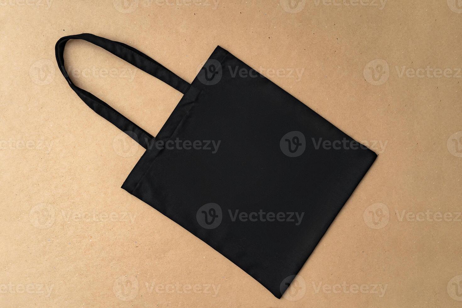 Black textile shopping bag on beige background flat lay photo