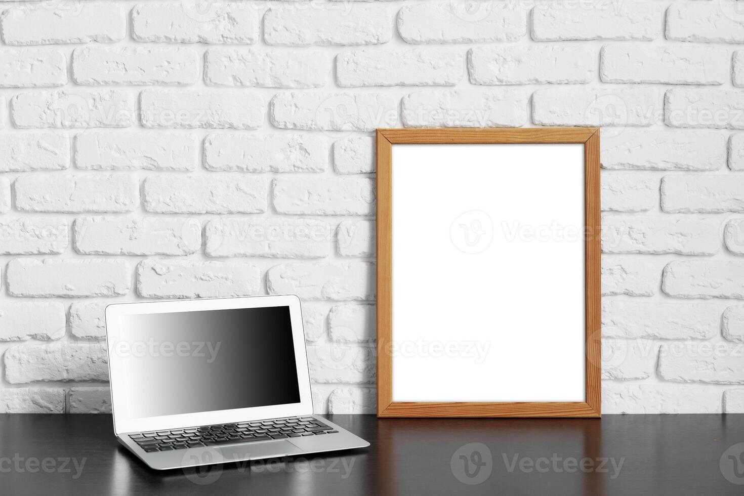 Worktable with laptop, stationery and decorations in home office with blank photo frame