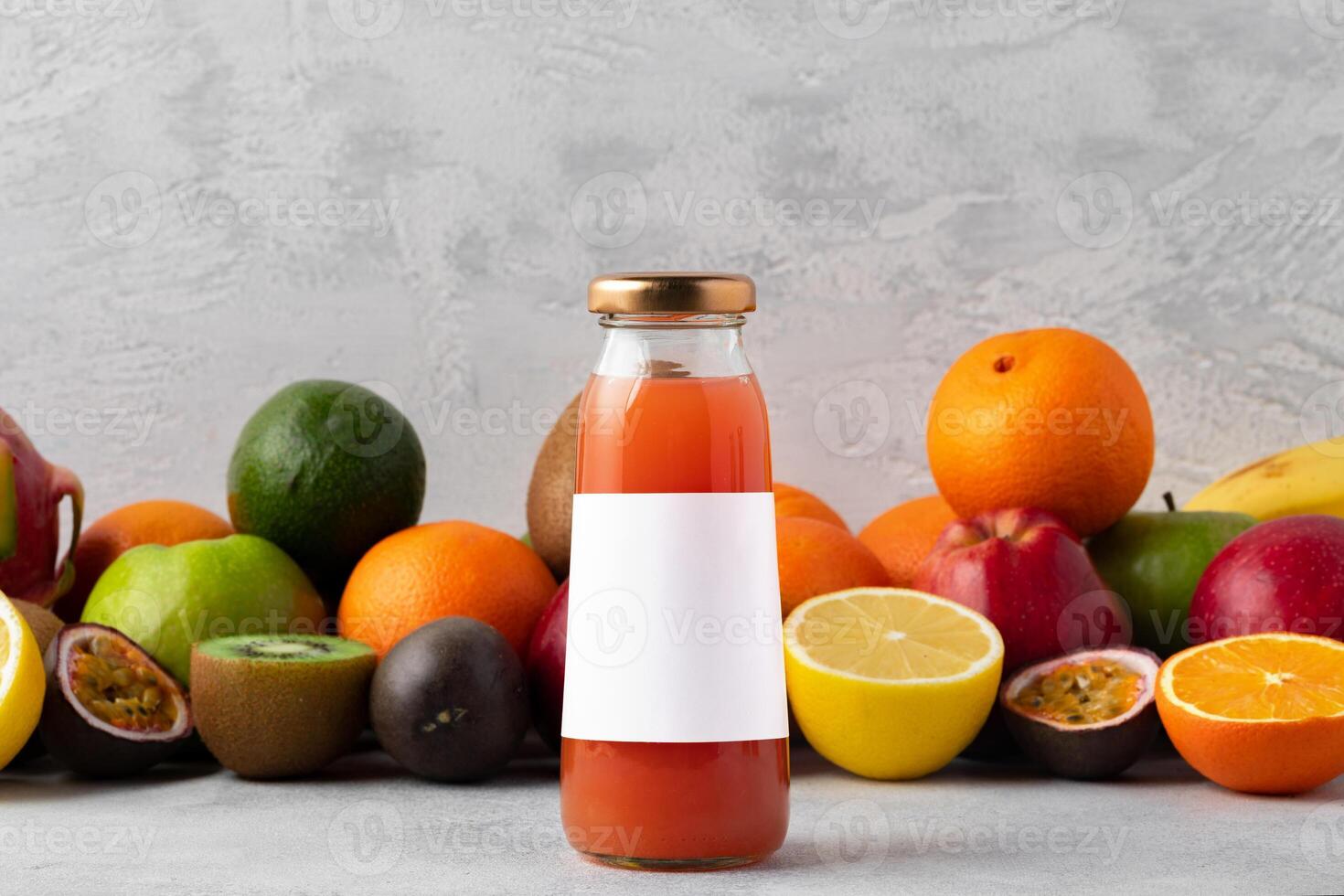 Various fruits and freshly squeezed fruits juice in bottle on gray background photo