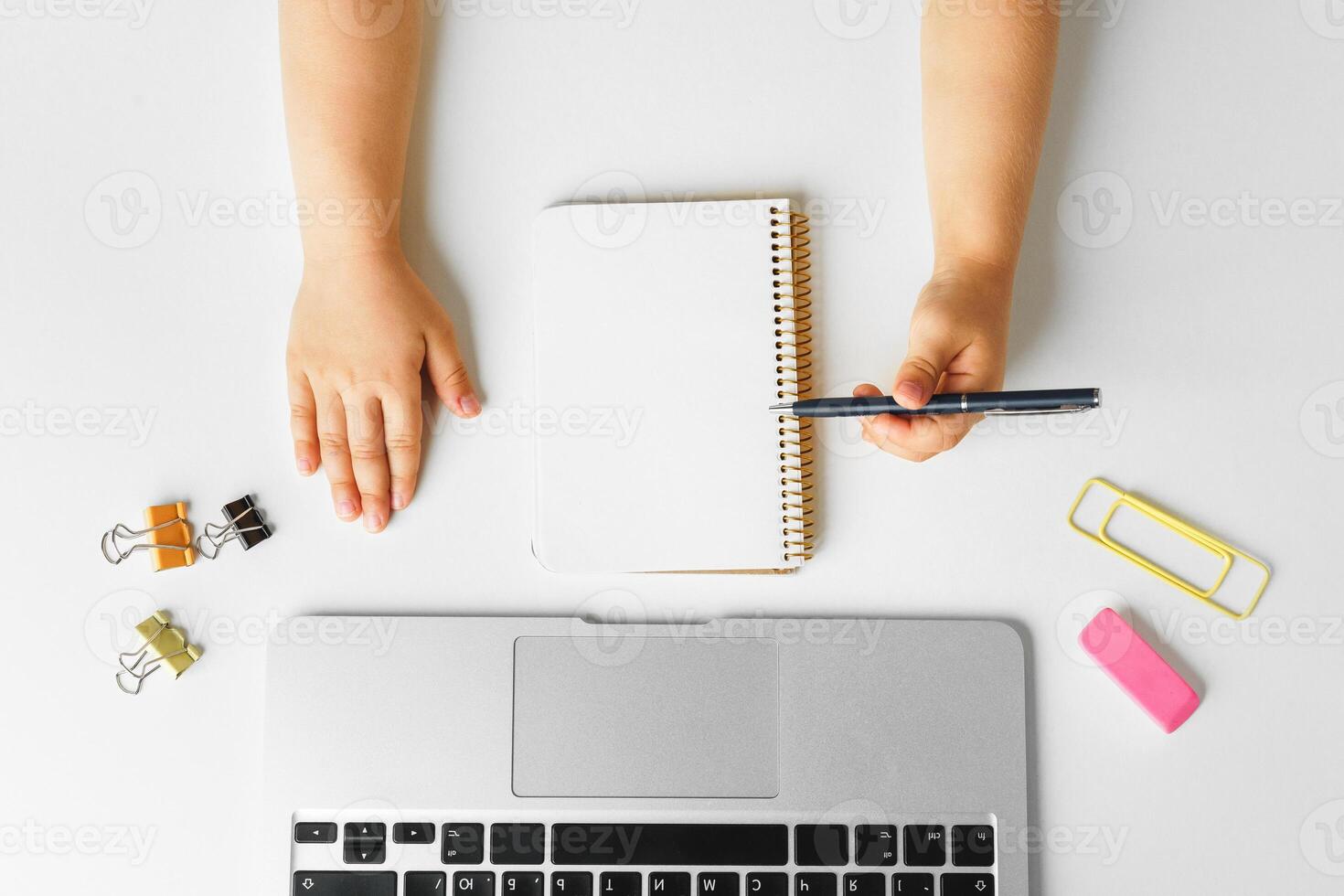 Kid's hands writing in open notebook, top view, copy space photo