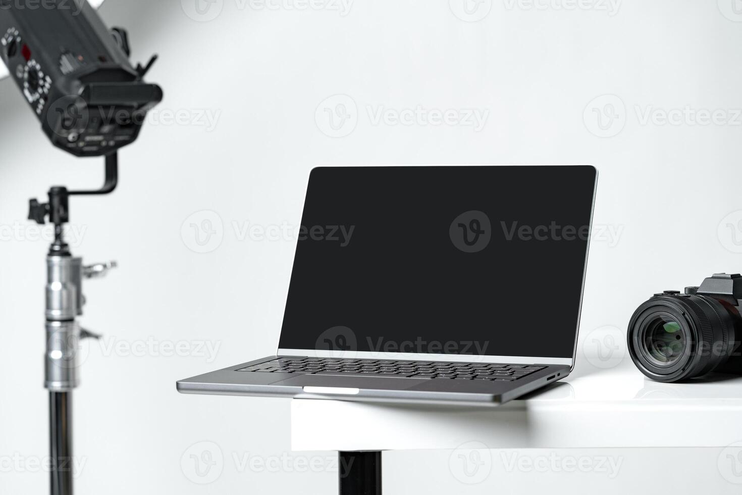 Laptop with black screen and photography equipment in photostudio photo