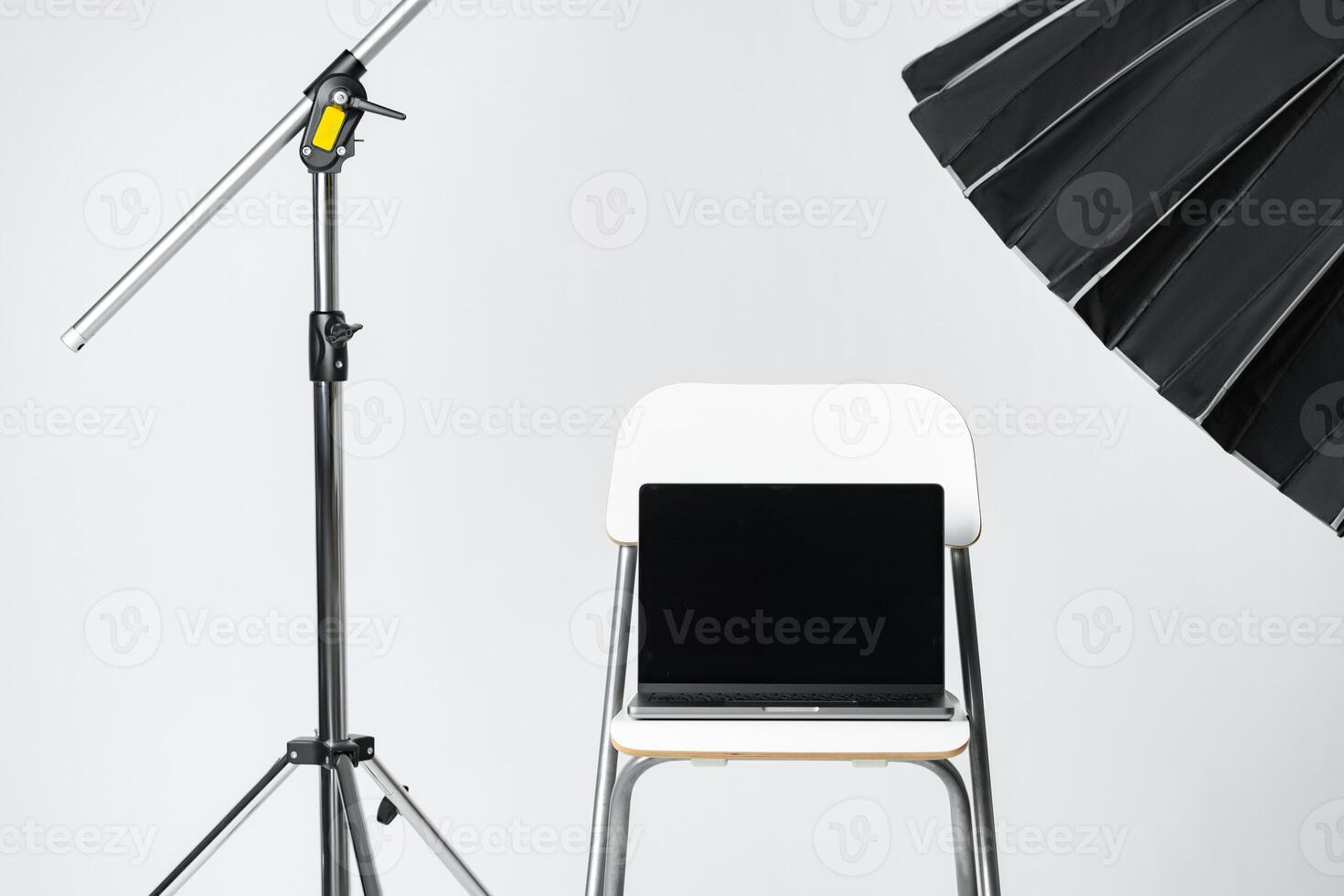 Laptop with black screen and photography equipment in photostudio photo