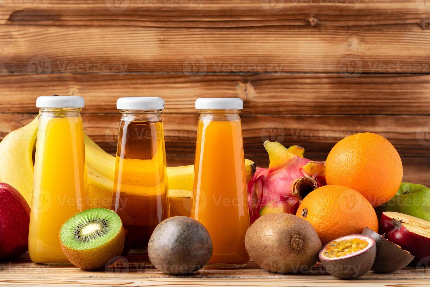 Fruit drink in glass bottle and frsh fruits on wooden background photo