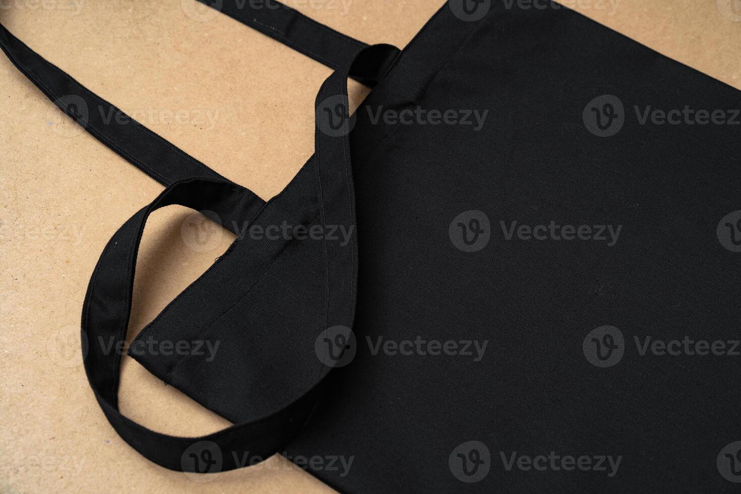 Black textile shopping bag on beige background flat lay photo
