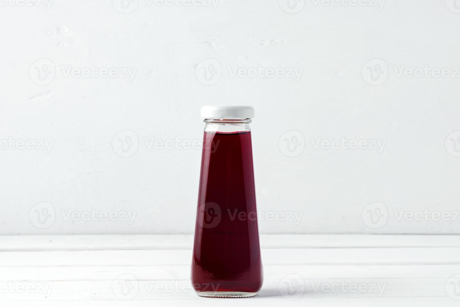 Small glass bottle of fresh juice on white background photo