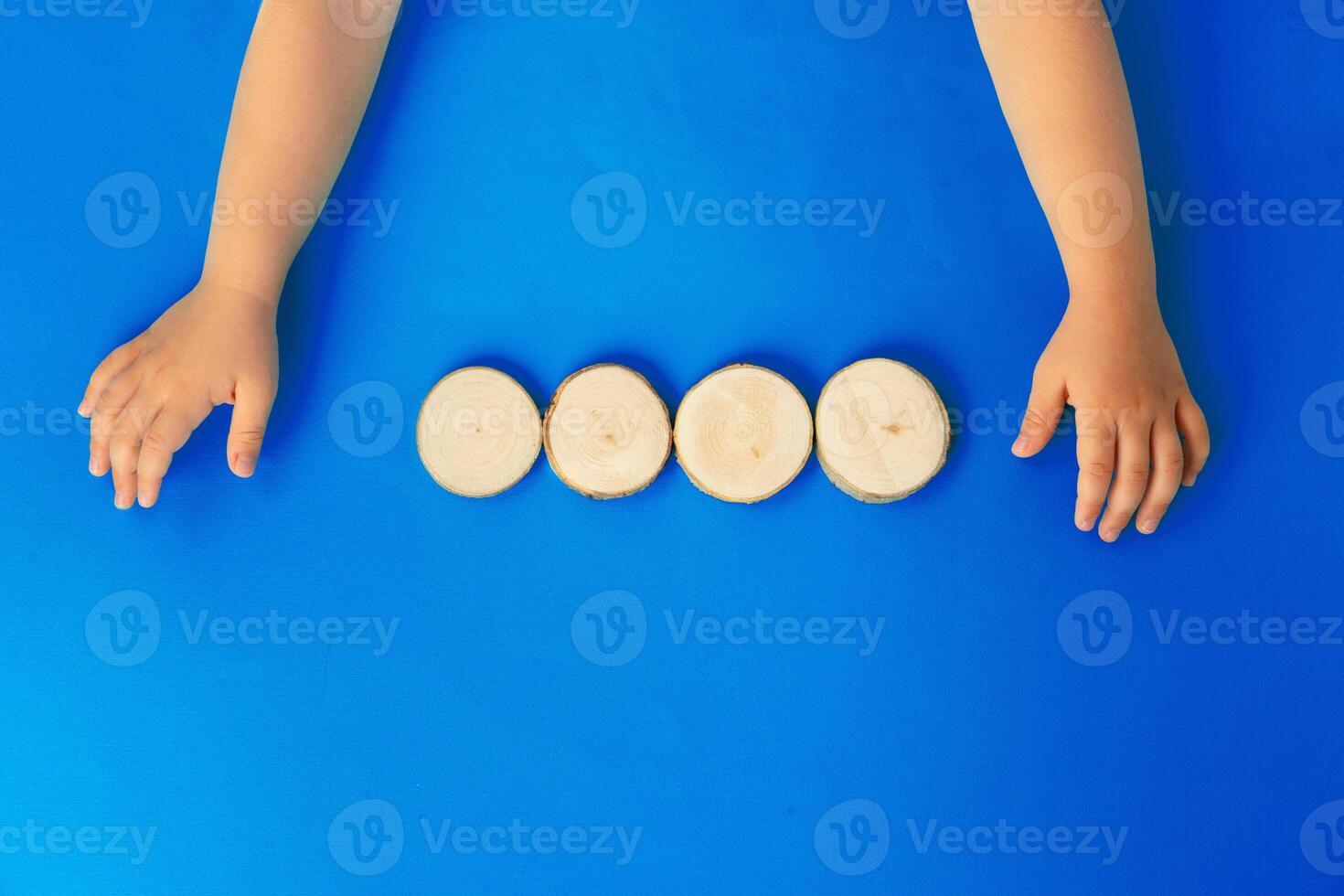 Hands of a kid with four wooden blocks, top view photo