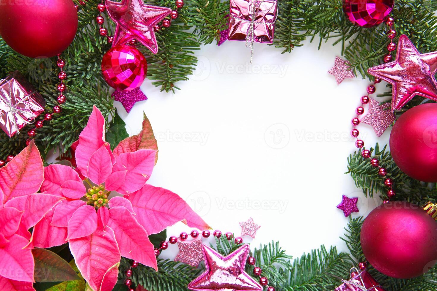 Festive Christmas arrangement featuring pink poinsettia, fir branches, pink and fuchsia ornaments, glittering stars and beads with empty white space in the center for text for holiday themed projects photo