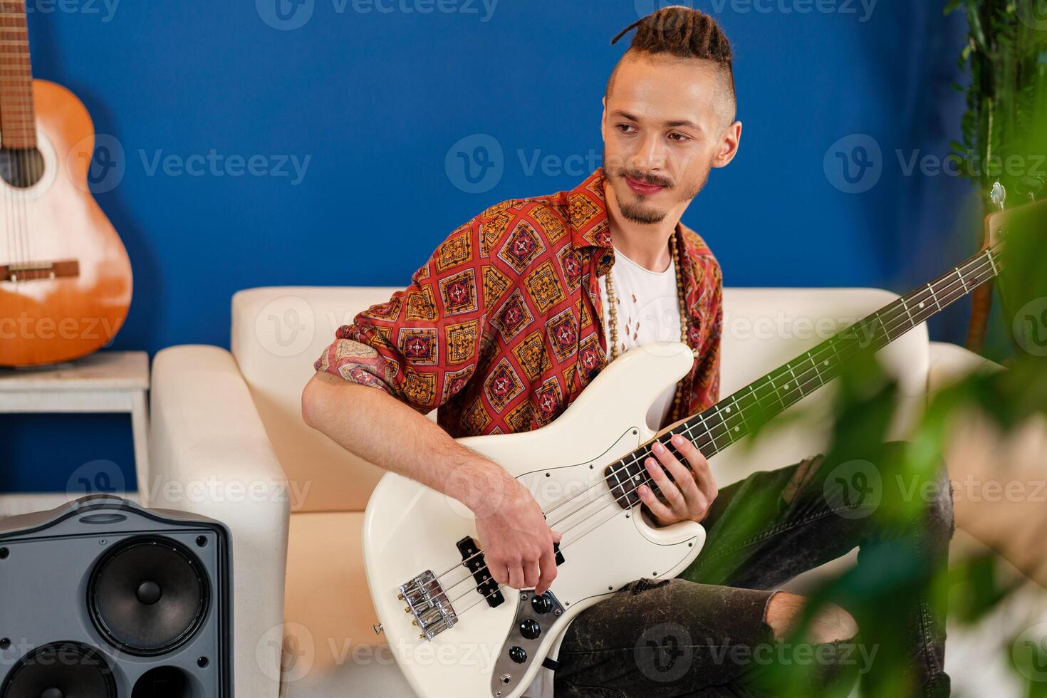 Young man guitar player sitting and performing on a couch photo