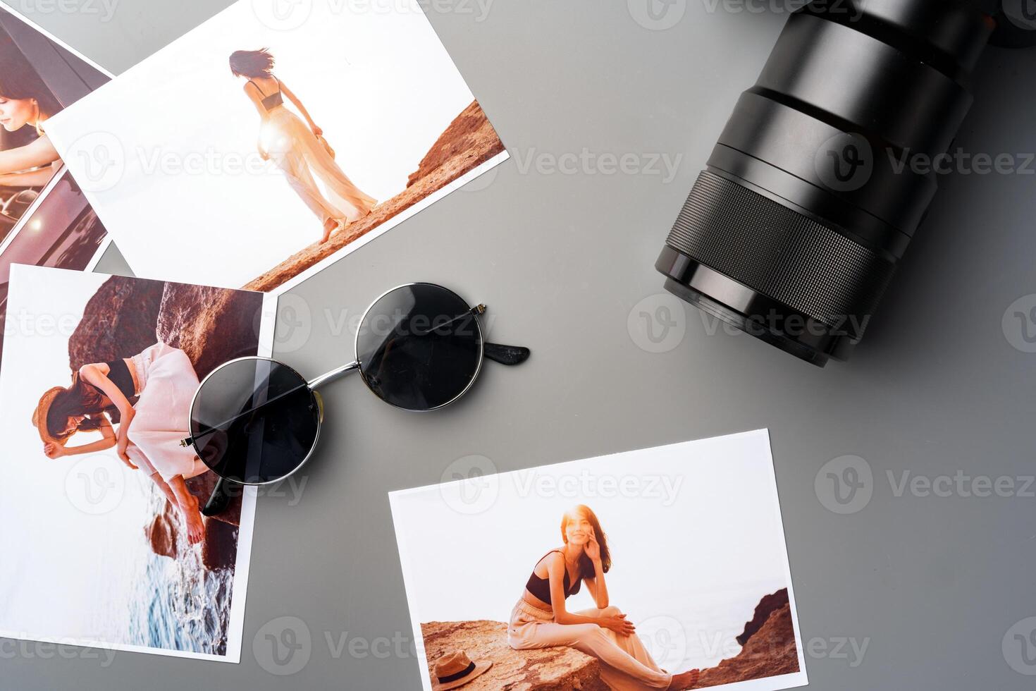 Photo camera with colorful printer photos on gray desk