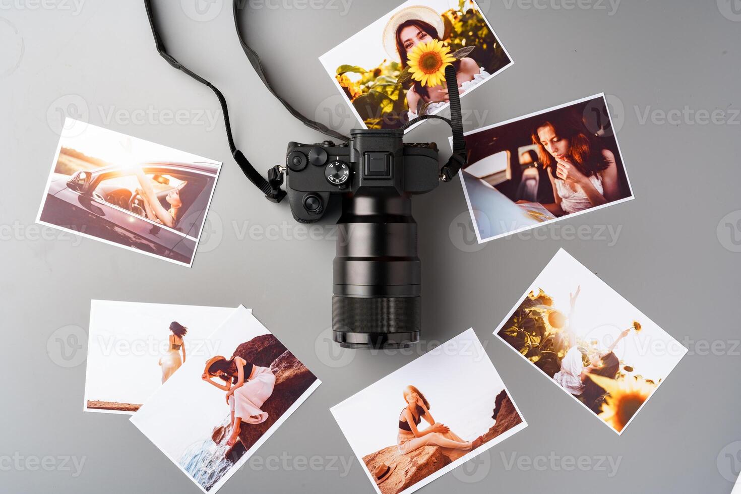 Photo camera with colorful printer photos on gray desk