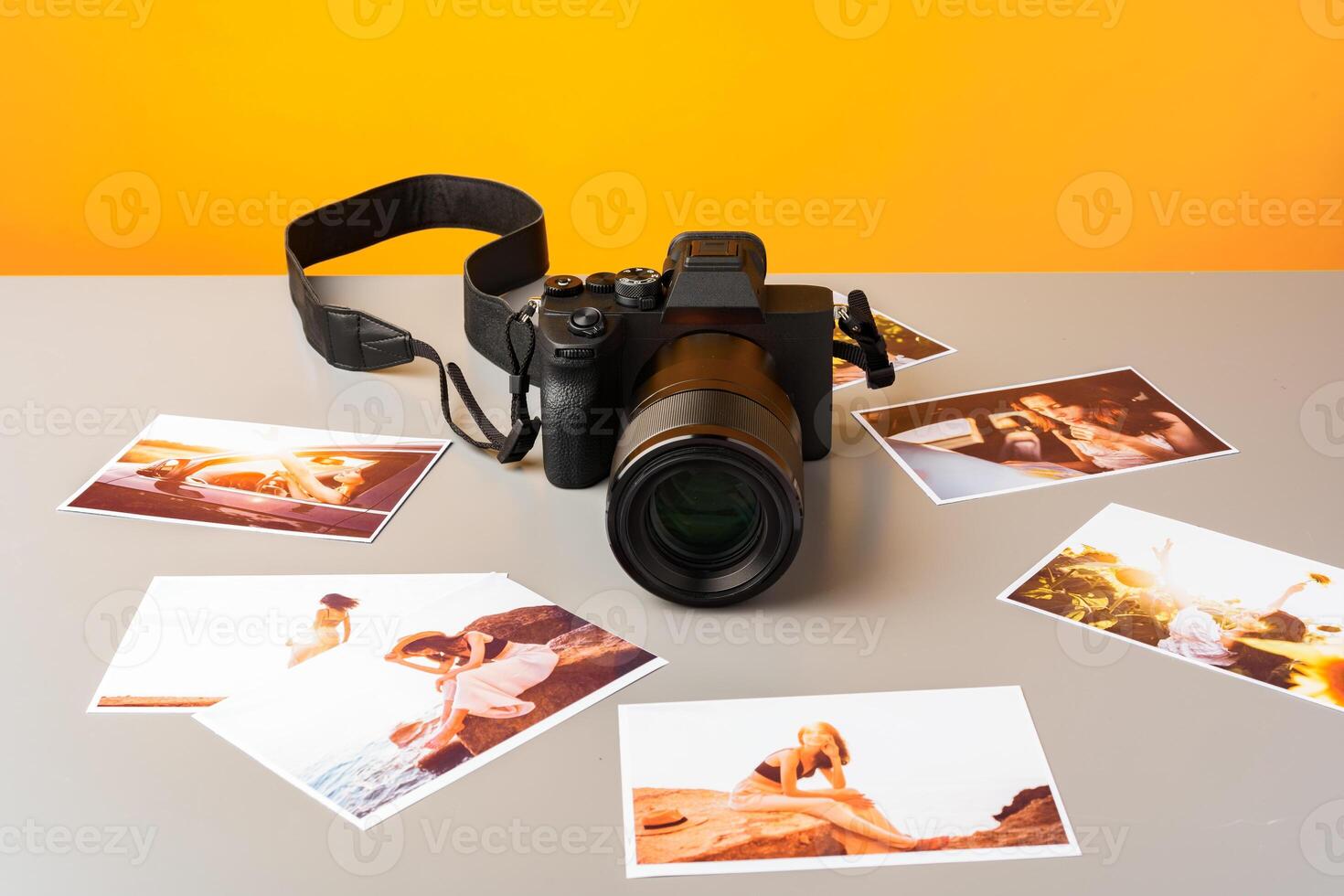 Photo camera with colorful printer photos on gray desk