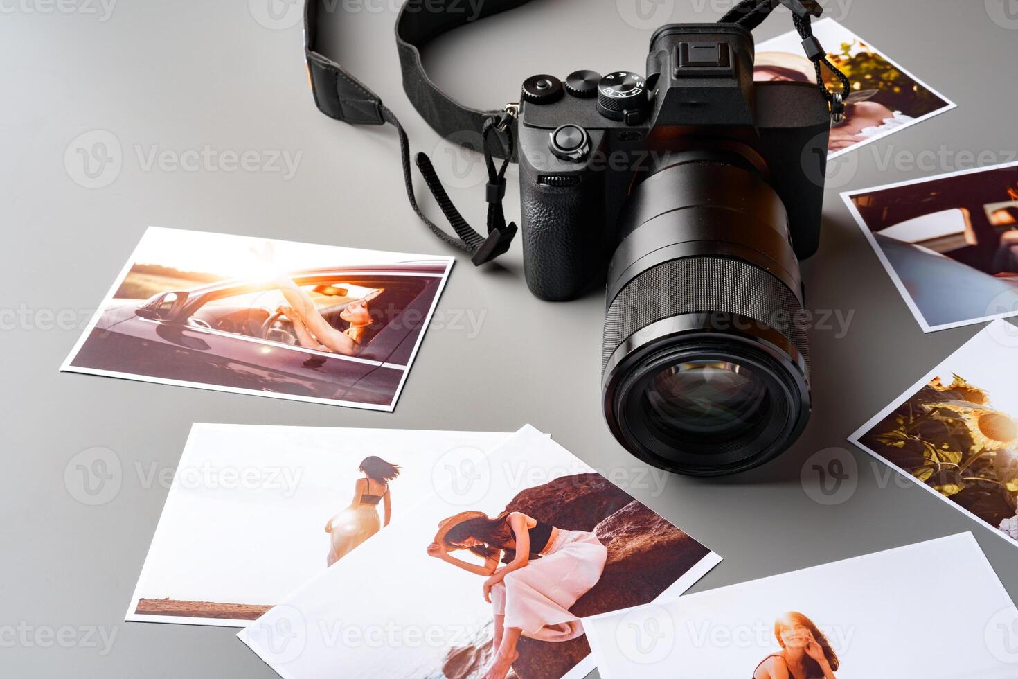 Photo camera with colorful printer photos on gray desk