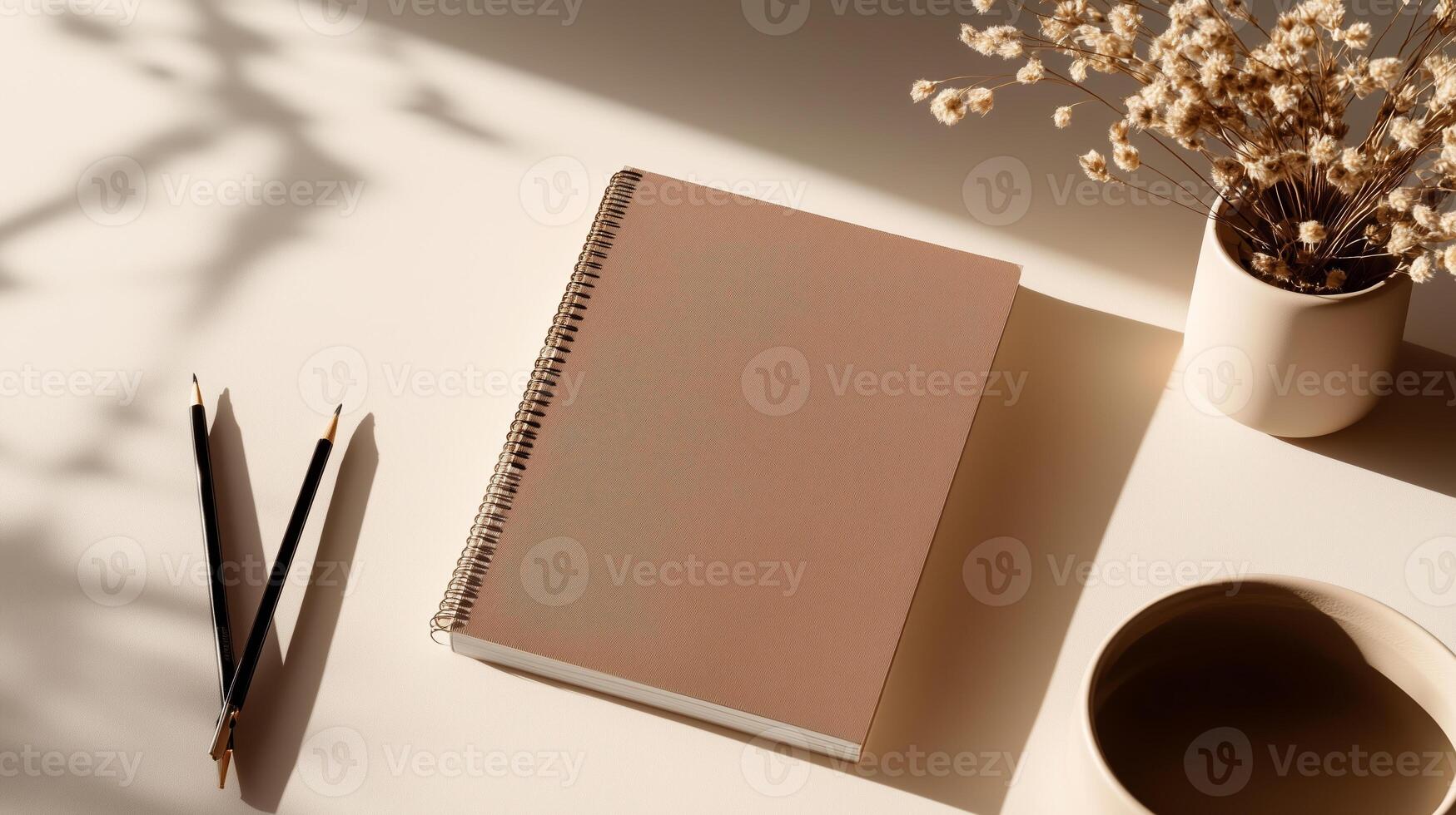 Soft sunlight shines on a minimalist workspace with a notebook, pens, and a flower vase photo