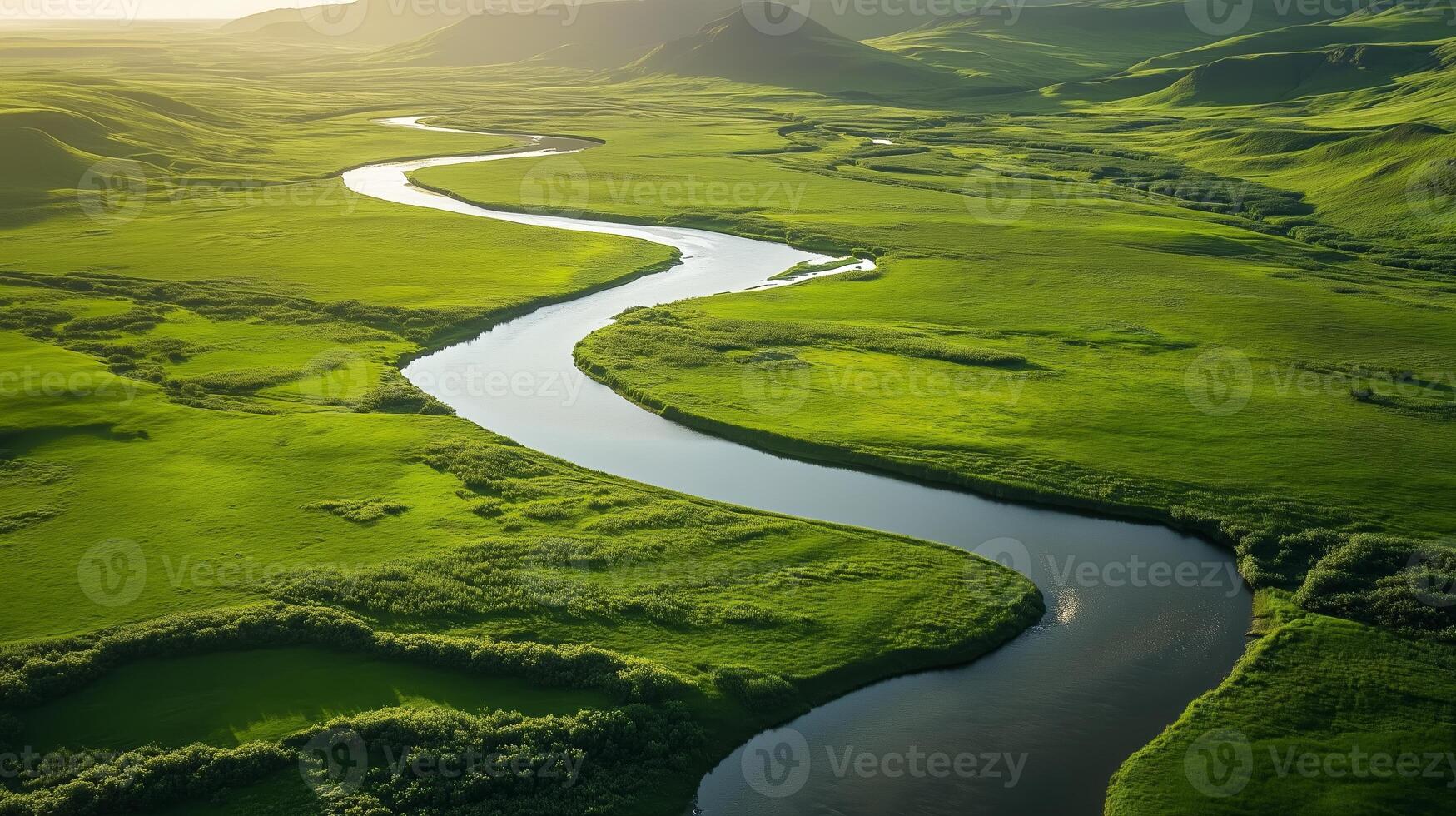 Vast green landscape with winding river under soft sunlight during golden hour photo