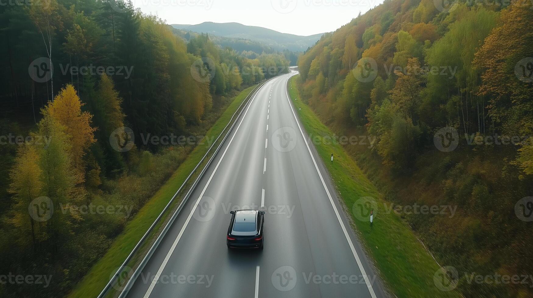 Scenic drive on a winding country road surrounded by autumn foliage and hills in the early morning photo