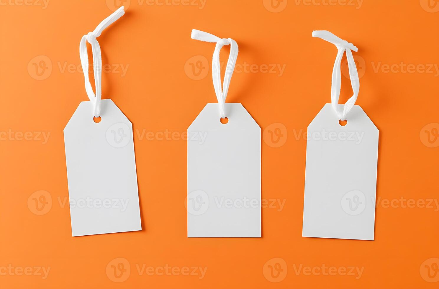 Three Blank White Tags with White Strings on an Orange Background photo