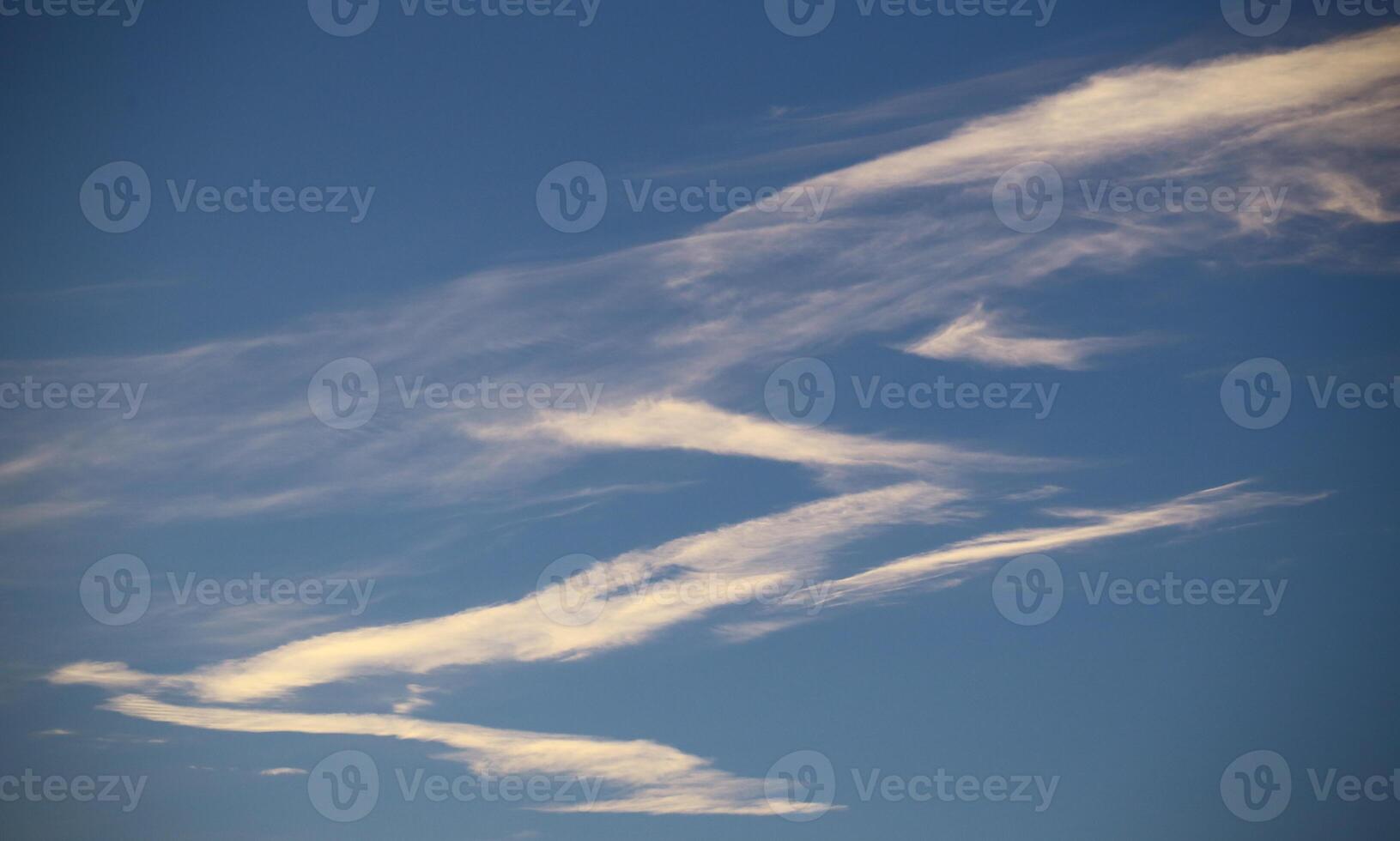 Zigzag shaped band of cirrus clouds on blue sky photo