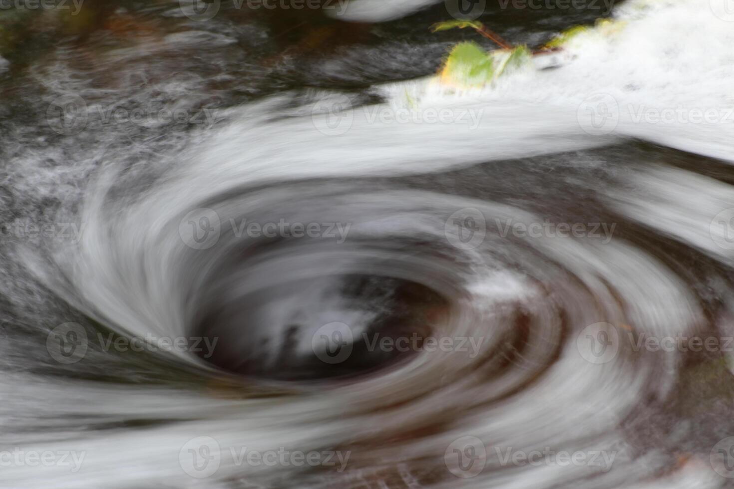 Blurred vortex in water with spray and a birch twig photo