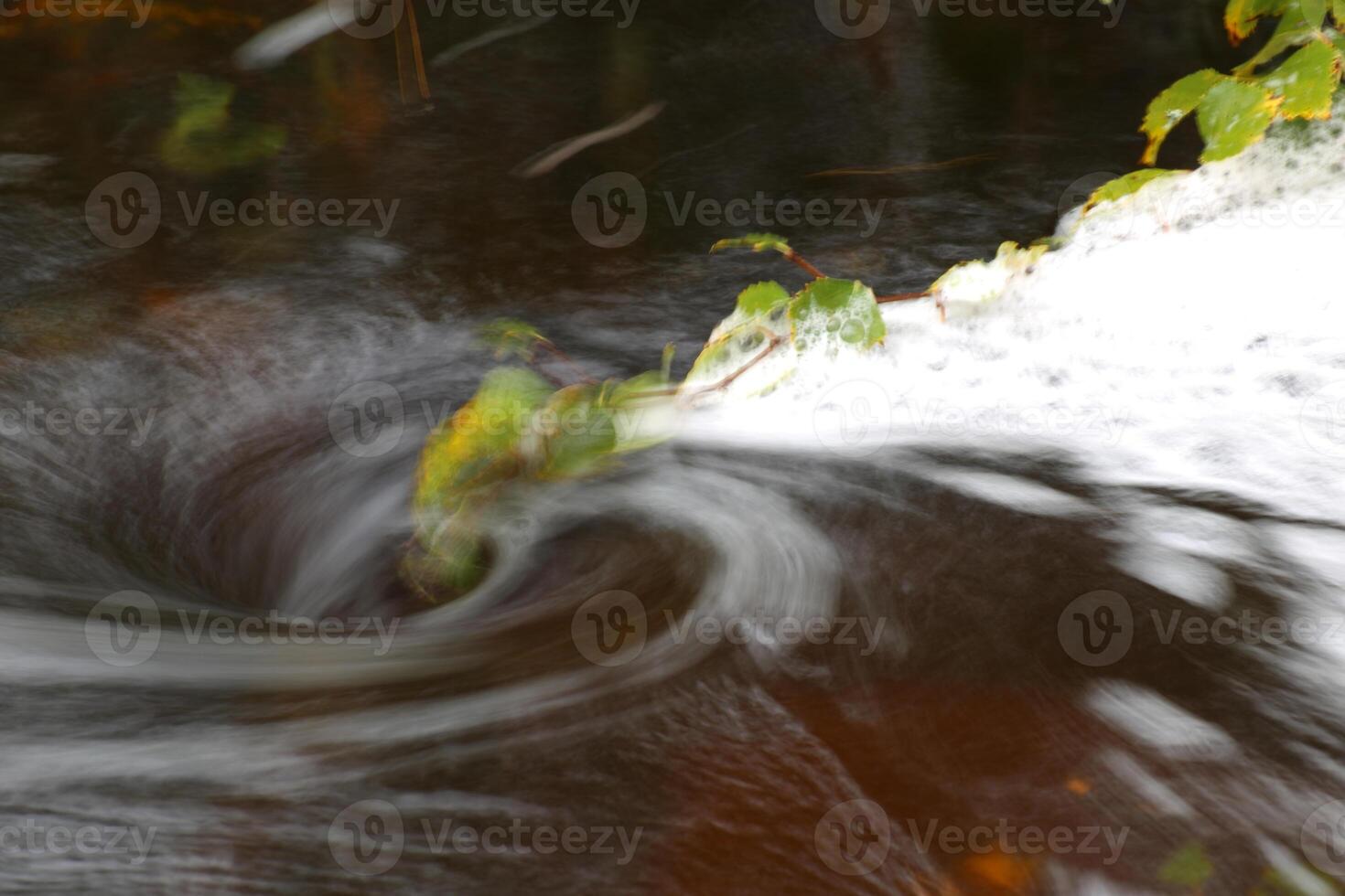 Blurred vortex in water with spray and a birch twig photo