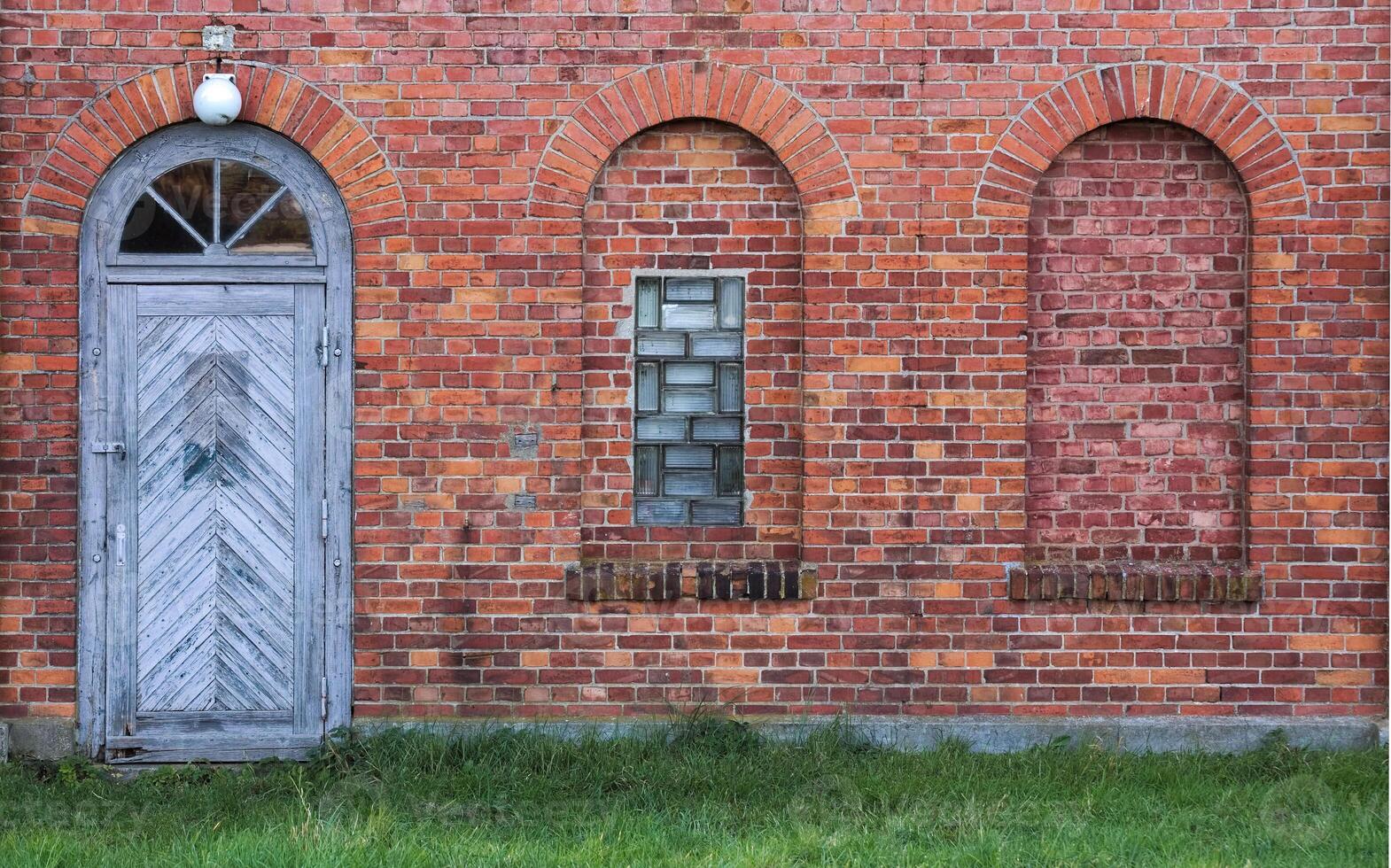 Arches and door in a wall made from red bricks photo