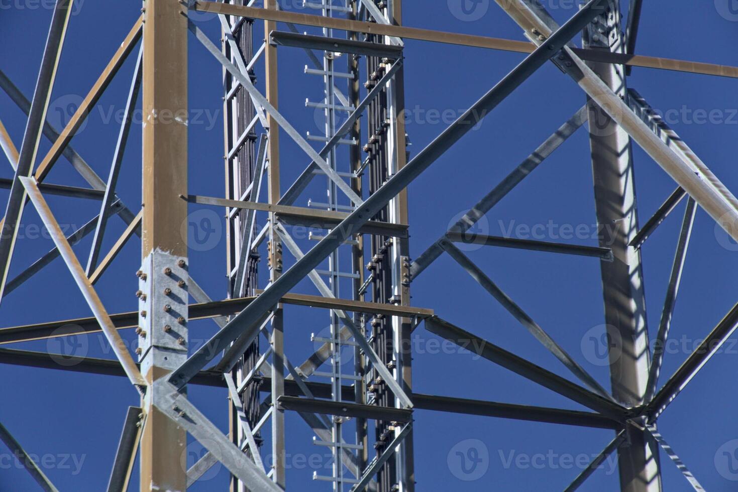 Metal frame of telecommunications tower in front of a dark blue sky photo