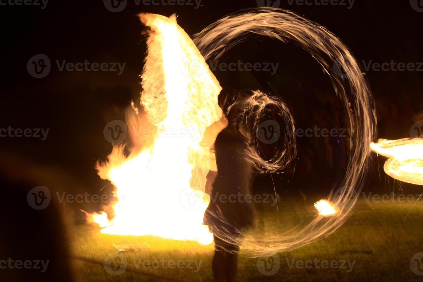 Long exposure shot of moving burning torches and fire with vague silhouette of a person photo