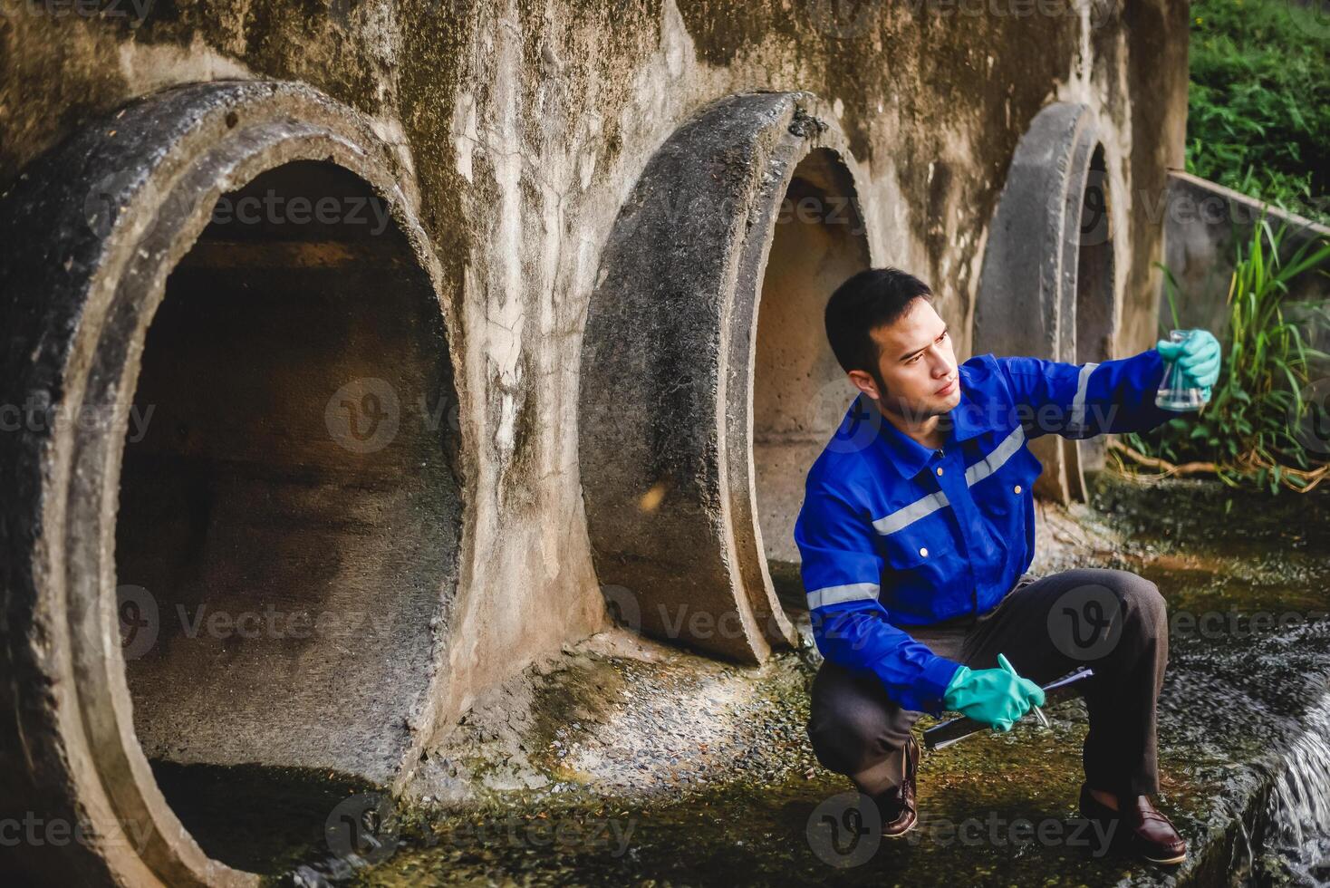 A water resource engineer checks the purity of water in a scientific glass bottle and records it on paper. photo