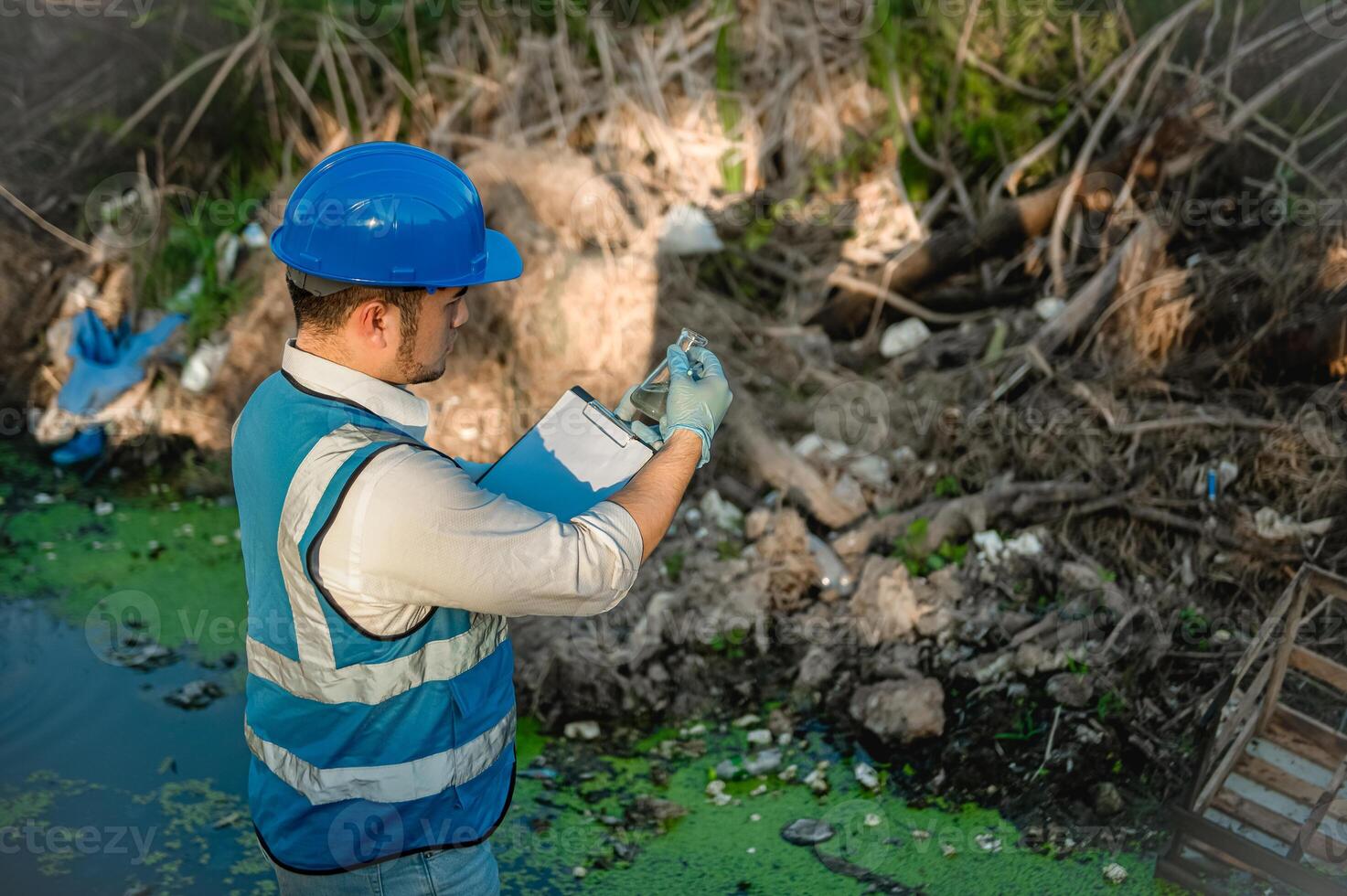 Environmental engineers inspect the purity of a canal in a community that is full of garbage and other objects mixed in the canal. photo