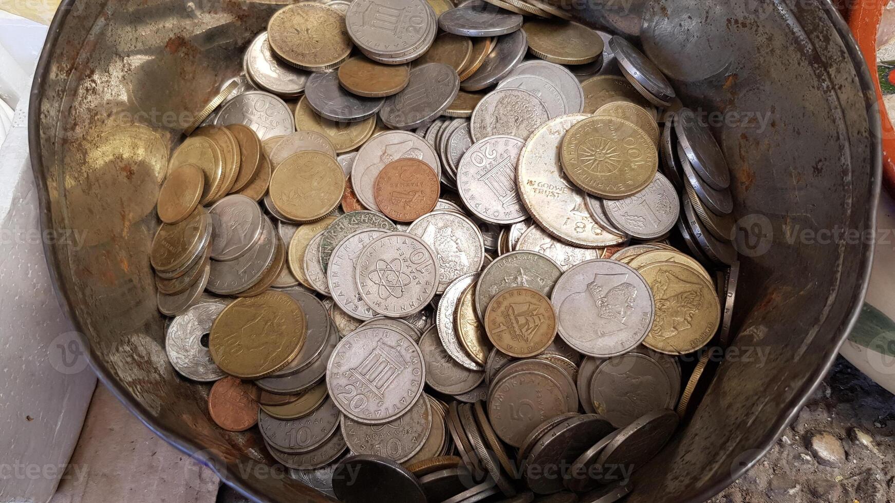 Vintage drachma coins closeup inside old tin can at flea market in Athens. Various Greek coins used before euro currency. Numismatic collection of obsolete coins of Greece money photo