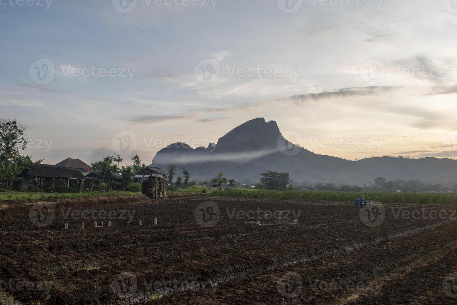 Morning vibe in the countryside with farmland ready for planting and foggy mountain in the background. A serene atmosphere in rural area in the early morning photo