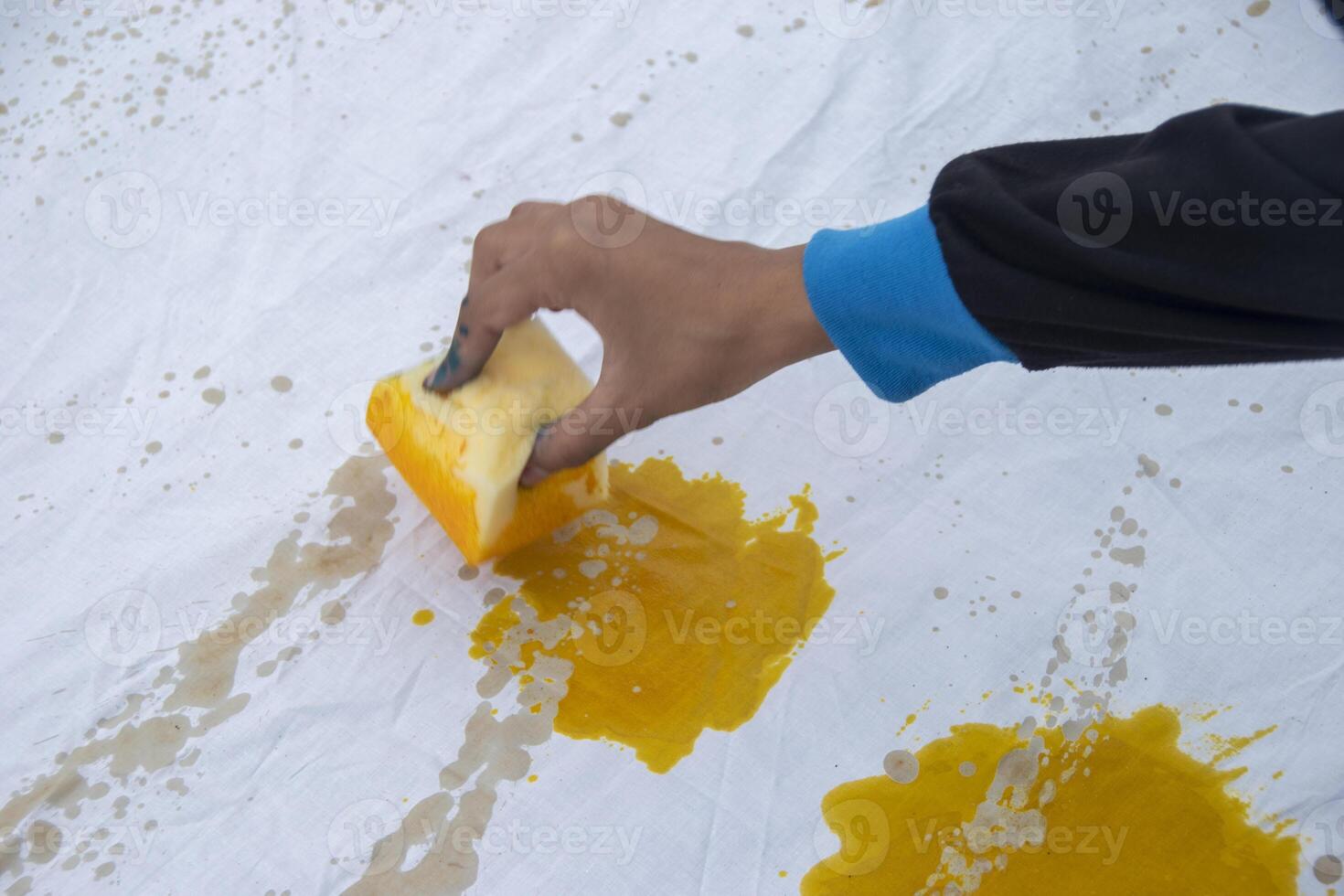 A person is coloring a piece of white cloth using a sponge. Students' creativity in making handicrafts using cloth as a medium at the Batik Ciprat Tulungagung Festival. photo