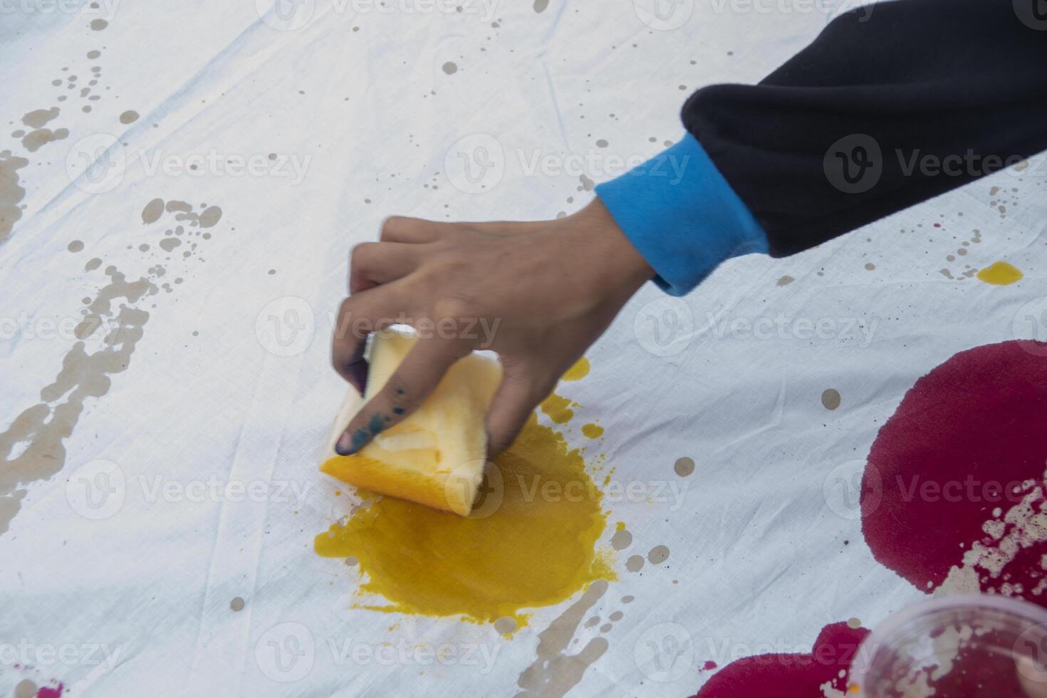 The process of coloring a piece of white cloth using a sponge. Students' creativity in making handicrafts using cloth as a medium at the Batik Ciprat Tulungagung Festival. photo