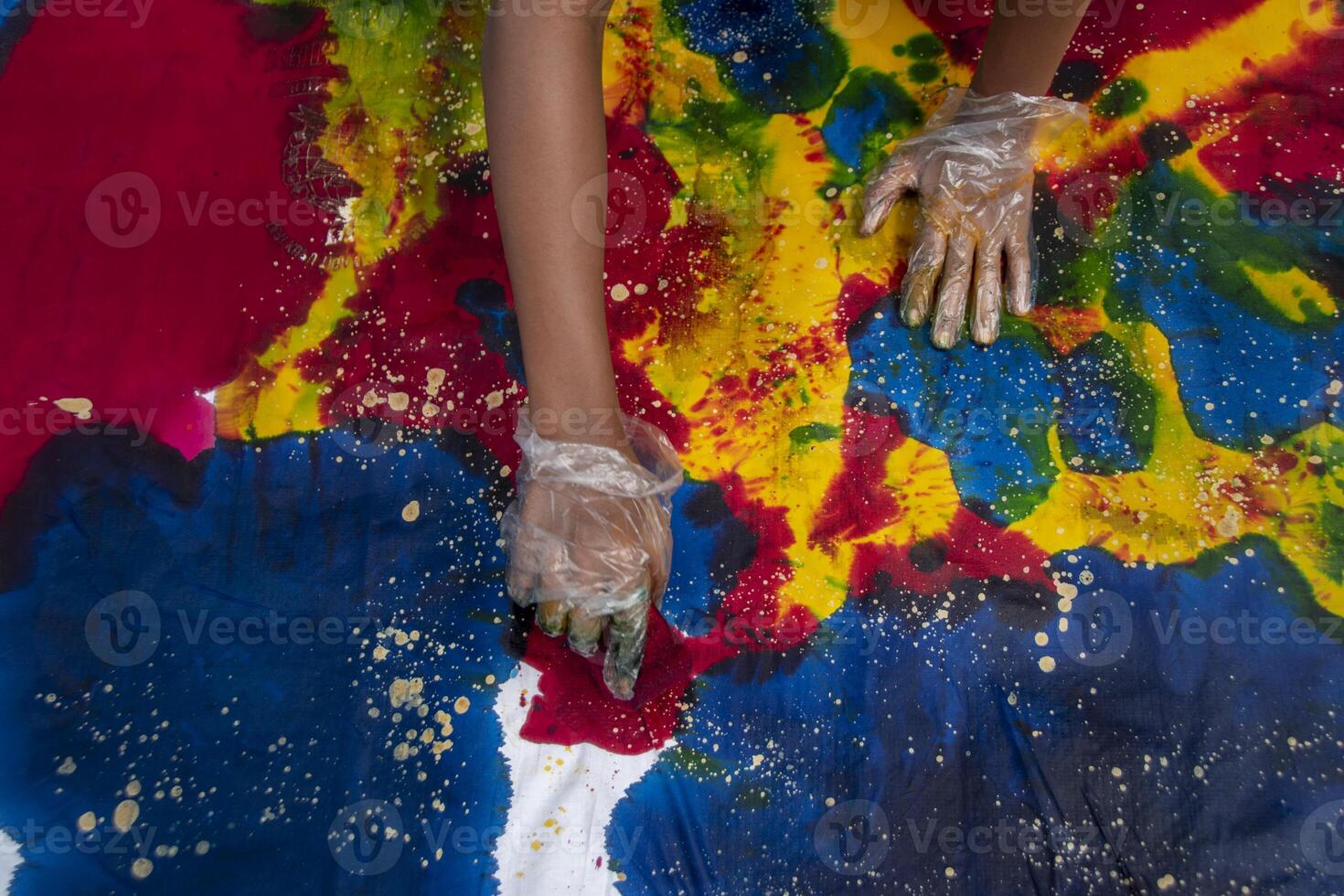 Someone wearing plastic gloves is coloring a piece of white cloth with textile dye. Creativity in making handicrafts using cloth as a medium. photo