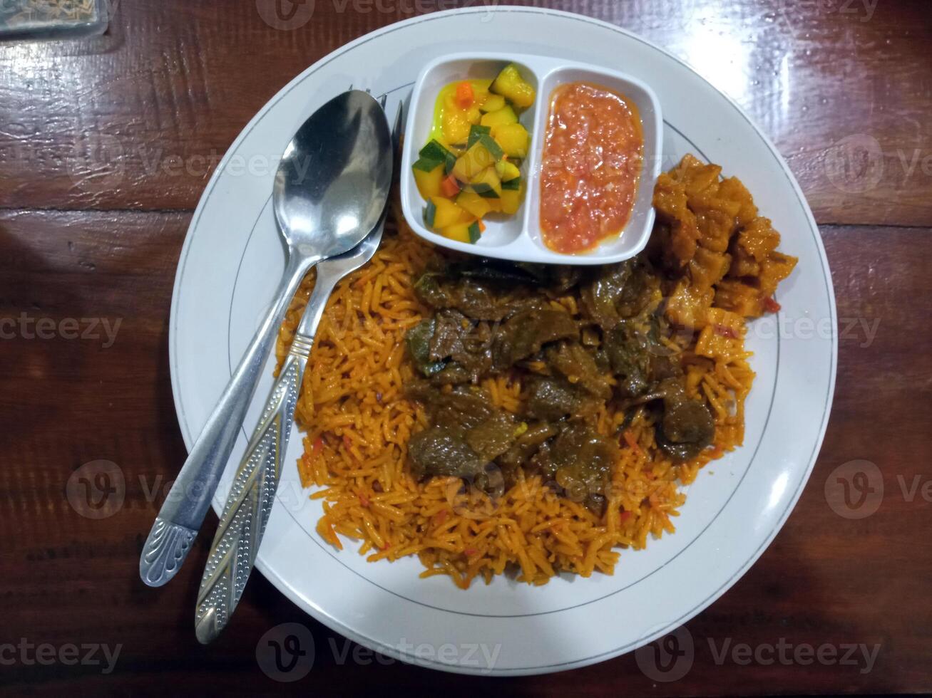 Flat lay view of Mutton Biryani, a highly popular dish in South Asia made from rice, meat, vegetables, spices and pickles. photo
