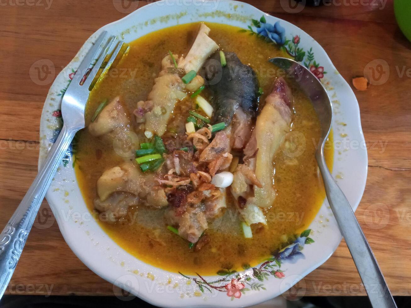 Flat lay view of gulai kikil, a spicy Indonesian dish of curry cow or goat's feet with thick coconut milk and spices. photo