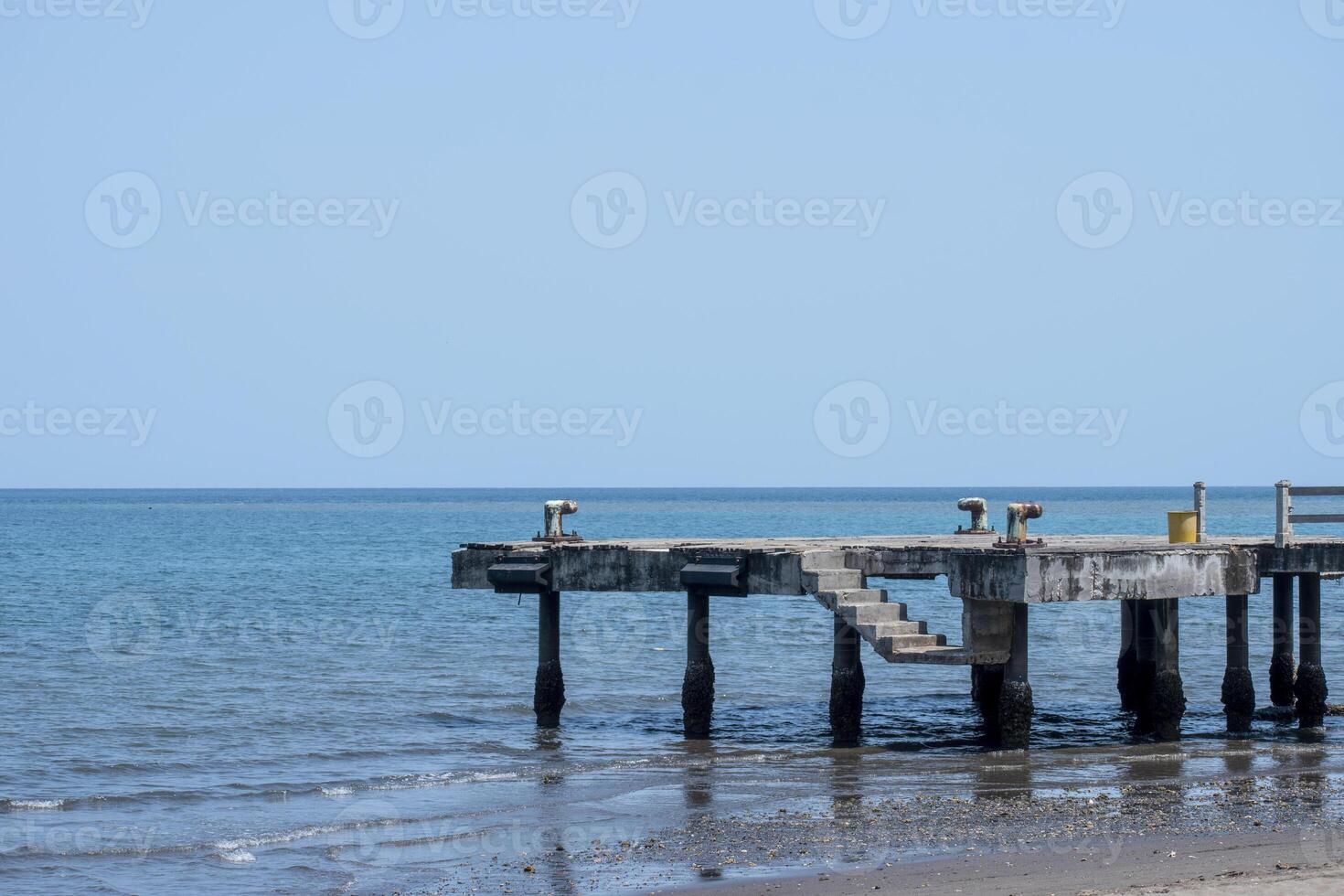 An empty abandoned dock with blue sea under the blue sky in the background. photo
